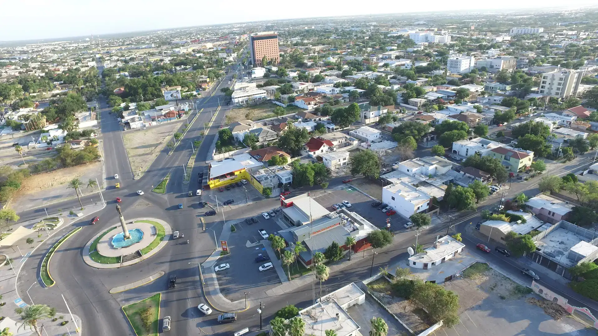 Vista aérea de la ciudad de Nuevo Laredo, mostrando una rotonda central y las calles aledañas, destacando el desarrollo urbano.